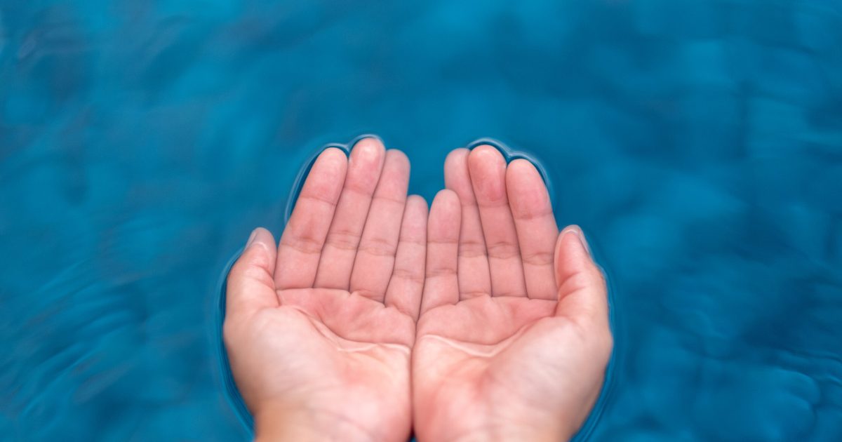 Closeup image of hands scooping clear water